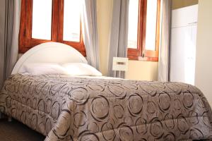 1 dormitorio con 1 cama con cabecero blanco y ventanas en Arequipa Suites Plaza, en Arequipa