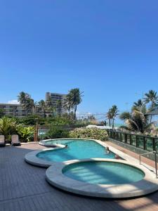 una piscina in un resort con persone di Coral Ritz - Flat beira mar (Condomínio Ritz Suites Home Service) a Maceió