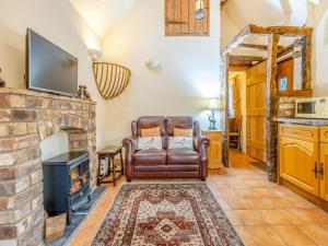 a living room with a fireplace and a leather chair at Rickyard Cottage- Uk45535 in Buildwas