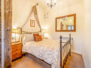 1 dormitorio con cama y espejo en Rickyard Cottage- Uk45535, en Buildwas