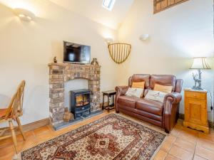 a living room with a couch and a fireplace at Rickyard Cottage- Uk45535 in Buildwas