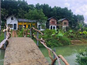 eine Brücke über einen Fluss vor den Häusern in der Unterkunft Stella Đồng Lâm Homestay in Làng Ben