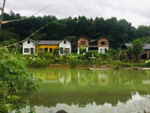 eine Gruppe von Häusern neben einem Wasserkörper in der Unterkunft Stella Đồng Lâm Homestay in Làng Ben