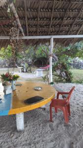 a wooden table and a chair on the beach at Pousada Panela Cheia 