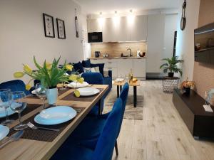 a dining room and living room with a table and blue chairs at Comfortable apartment for 5 people, Dar ówko in Darłówko