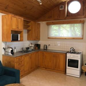 cocina con armarios de madera y horno de fogón blanco en Copeland Cabins en Copeland