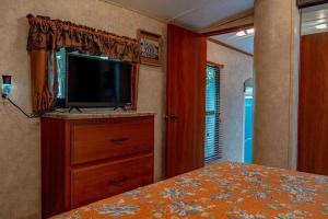 1 dormitorio con cama y vestidor con TV en Little RV on the Lake, en Lutz