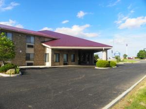 un bâtiment avec un toit rouge et un parking dans l'établissement Royalton Inn & Suites Upper Sandusky, à Upper Sandusky
