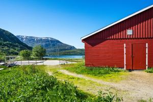 um celeiro vermelho com uma estrada de terra ao lado em Storjord Farmstay Ranchhouse em Kvaløya