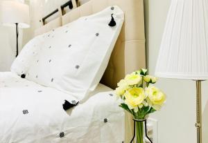 - un lit avec des oreillers blancs et un vase de fleurs jaunes dans l'établissement Private Guest Studio w/ Full Bath - Queen Bed - Parking - Central Location, à Vancouver