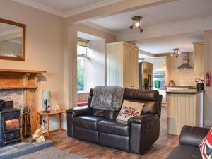 a living room with a leather couch and a fireplace at Caldhame Smiddy in Marykirk