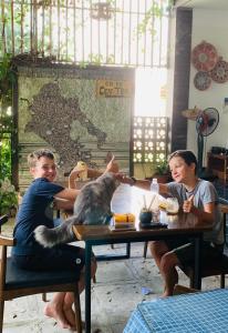 a group of people sitting at a table with a dog at Coto Center Homestay in Đảo Cô Tô