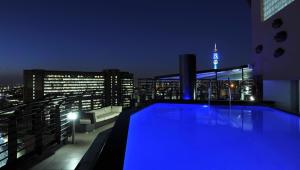 une piscine sur le toit d'un bâtiment la nuit dans l'établissement ANEW Hotel Parktonian Johannesburg, à Johannesbourg
