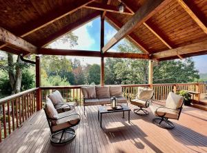 a porch with a couch and chairs on a wooden deck at Misty Mountains Lodge in Ronceverte