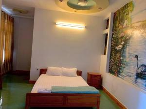 Schlafzimmer mit einem Bett mit Wandgemälde in der Unterkunft MẠNH LÊ GIA HOTEL in Plei Brel (2)