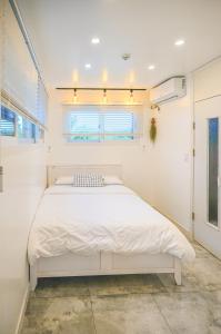 a white bedroom with a large bed in a room at Jeju Love Stay Purple in Jeju