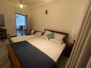 a bedroom with a large bed with white and green pillows at Arcadia House Hanthana in Kandy