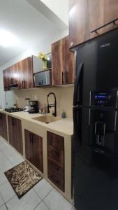 a kitchen with a black refrigerator and wooden cabinets at Departamento AJAL TULUM in Tulum