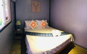 Dormitorio pequeño con cama con sábanas y almohadas blancas en Keira Backpackers, en El Nido