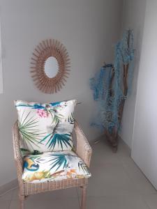 a rattan chair with a pillow and a mirror at A L'Arche Bleue in Le Robert