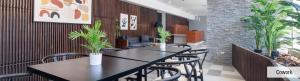 two tables and chairs in a room with plants at Open House Apart Centro Iquique in Iquique