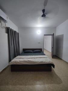 um quarto com uma cama grande num quarto branco em Independent 2-Room with Kitchen Homestay em Dehradun