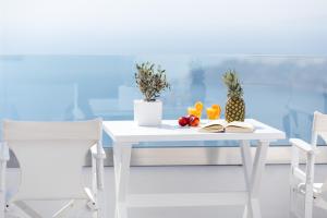 a white table with fruit on it with two chairs at Unique Suites in Imerovigli