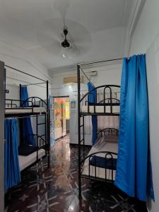 アンジュナにあるThe goanvibes hostel and cafeの青いカーテン付きの二段ベッド3台が備わる客室です。