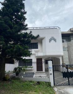 Biały dom z płotem i drzewem w obiekcie Burgitos Homescape Tagaytay w mieście Tagaytay