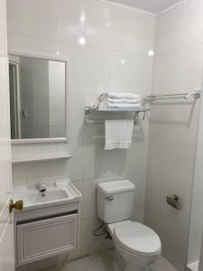 a white bathroom with a toilet and a sink at Burgitos Homescape Tagaytay in Tagaytay