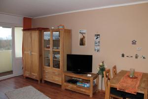 ein Wohnzimmer mit einem TV und einem Holzschrank in der Unterkunft Ferienappartement E612 für 2 Personen an der Ostsee in Brasilien