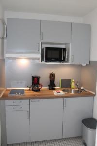 a kitchen with white cabinets and a sink and a microwave at Ferienwohnung F109 in Brasilien
