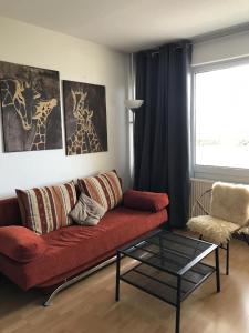 a living room with a red couch and a glass table at Ferienappartement K112 für 2-4 Personen in Strandnähe in Schönberg in Holstein