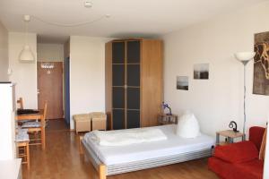 um quarto com uma cama branca e uma cadeira vermelha em Ferienappartement K112 für 2-4 Personen in Strandnähe em Schönberg in Holstein