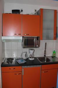 cocina con armarios de color naranja, fregadero y microondas en Ferienappartement K112 für 2-4 Personen in Strandnähe, en Schönberg in Holstein