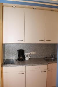 uma cozinha com armários brancos e uma cafeteira no balcão em Ferienappartement K1208 mit Ostseeblick em Brasilien