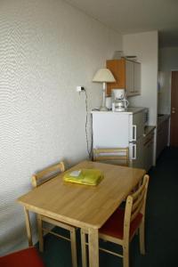 Schönberg in HolsteinにあるFerienappartement K1313 für 2-4 Personen mit Ostseeblickのキッチン(木製テーブル、椅子、冷蔵庫付)