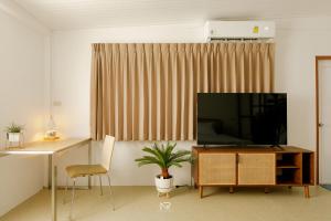 a living room with a flat screen tv and a chair at White house 36 Hatyai in Hat Yai