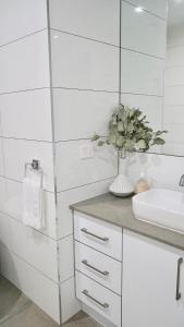 a white bathroom with a sink and a vase of flowers at Honeysuckle St Cottage Central Location Sleeps 8 - To be removed in Bendigo