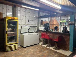 a kitchen with a refrigerator and a bar with red chairs at Chácara Recanto do Guerreiro em Aruja in Arujá
