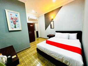 um quarto de hotel com uma cama grande e um cobertor vermelho em DAILY INN HOTEL em Mersing