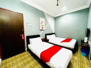 two beds in a room with red and white sheets at DAILY INN HOTEL in Mersing