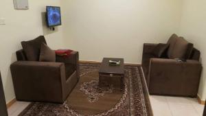 ein Wohnzimmer mit 2 Stühlen und einem Tisch in der Unterkunft العيرى للشقق المخدومه جيزان 3 in Dschāzān