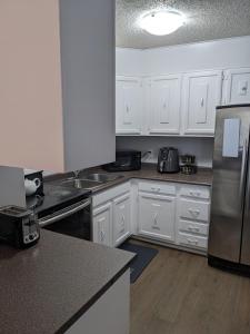 a kitchen with white cabinets and a stainless steel refrigerator at Bi-Level Suite in Saskatoon in Saskatoon