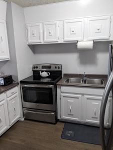 a kitchen with white cabinets and a stove and a sink at Bi-Level Suite in Saskatoon in Saskatoon