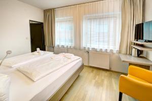 a bedroom with a large bed and a yellow chair at Hotel Hofmann in Salzburg