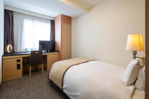 高崎的住宿－高崎大都會酒店，酒店客房配有一张床和一张书桌及一台电视