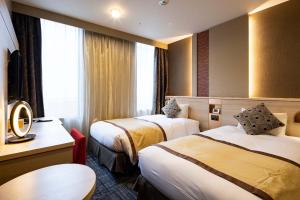 a hotel room with two beds and a table at Hotel Metropolitan Takasaki in Takasaki