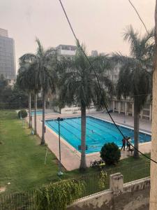 uma piscina com palmeiras junto a um edifício em Awasthi Kozi Stays B&B - closest to VFS em Nova Deli