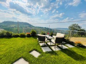 eine Terrasse mit zwei Stühlen und einem Tisch im Gras in der Unterkunft Casa Rafanelli in Monforte dʼAlba